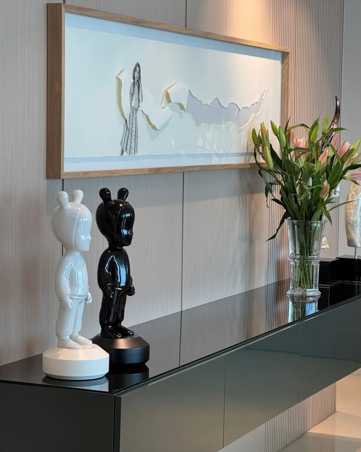 Credenza con arte enmarcado, figuras en blanco y negro y lirios