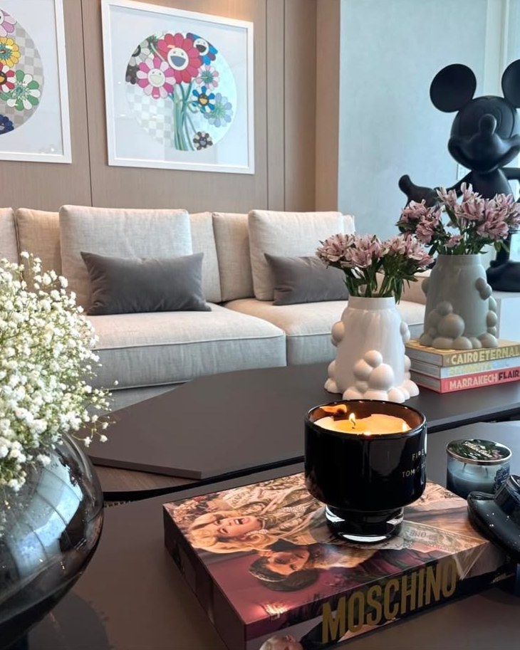 Vela encendida sobre libro de Moschino en una mesa de centro
