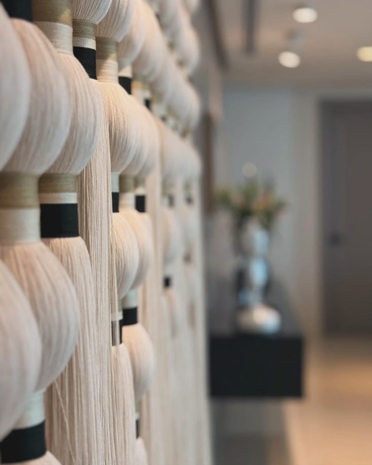 Muro decorativo de borlas tejidas en tonos crema