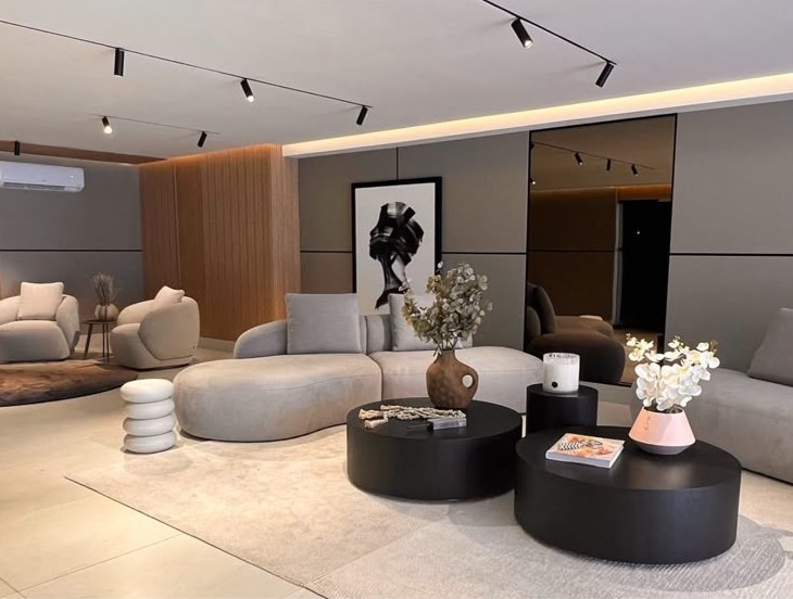 Lobby en Bahía del Golf con sofá curvo gris y mesas de centro negras