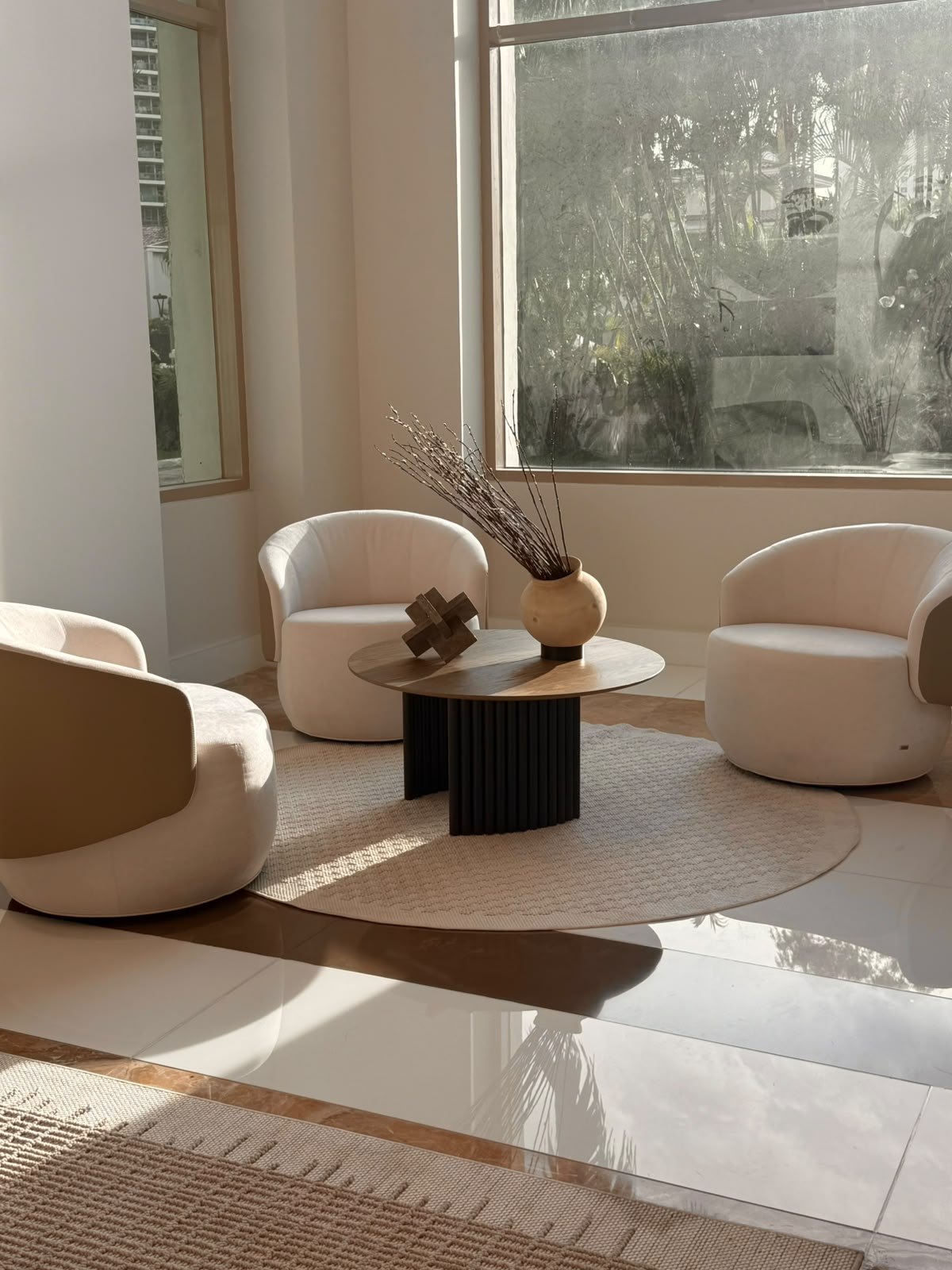 Sala de espera de lobby con butacas giratorias blancas alrededor de una mesa redonda de madera