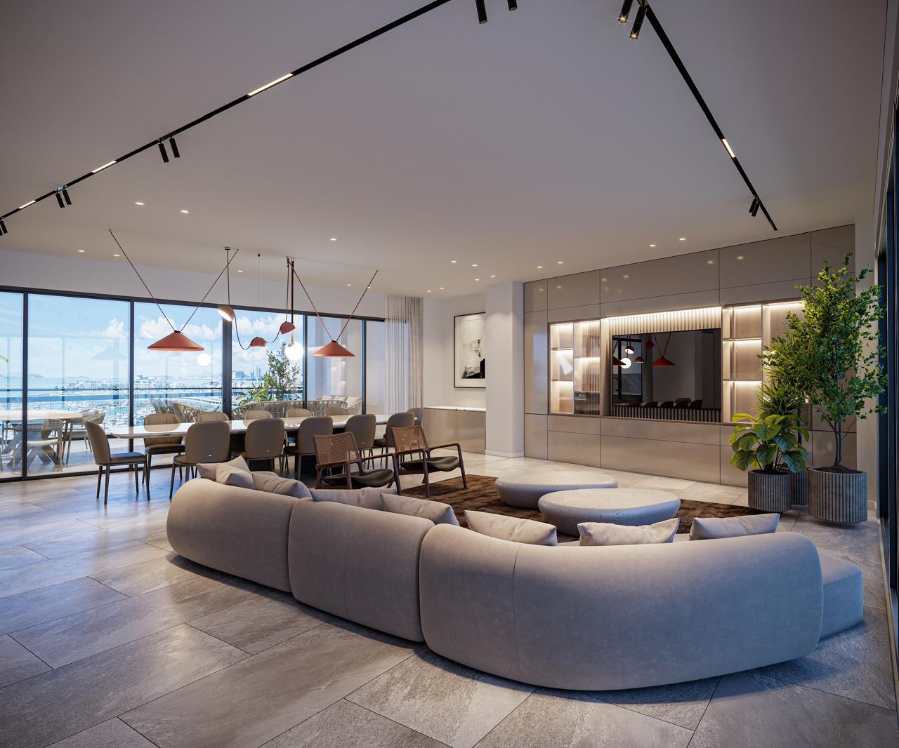 Sala y comedor de concepto abierto con sofá curvo frente a ventanales con vista a la bahía